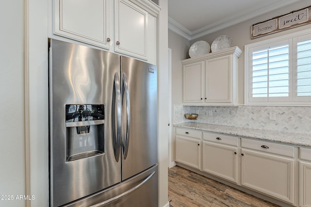 kitchen with tasteful backsplash, white cabinets, ornamental molding, stainless steel refrigerator with ice dispenser, and light stone countertops