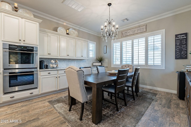 dining area featuring dark wood-type flooring, crown molding, and a notable chandelier