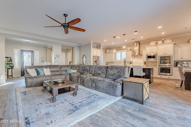 living room featuring crown molding, ceiling fan, and light hardwood / wood-style flooring