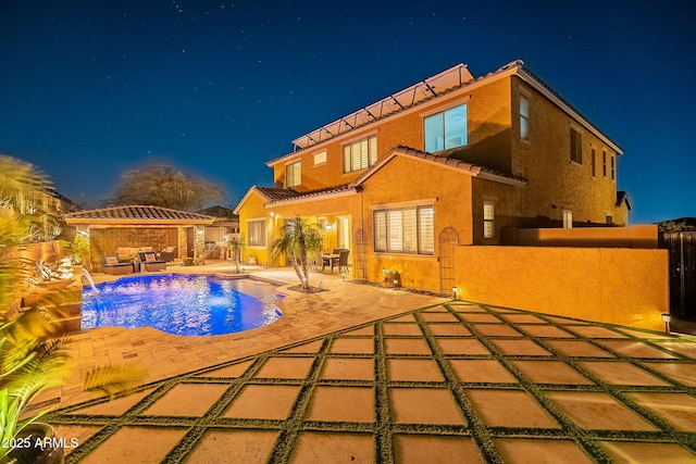 pool at night featuring a gazebo, pool water feature, and a patio area