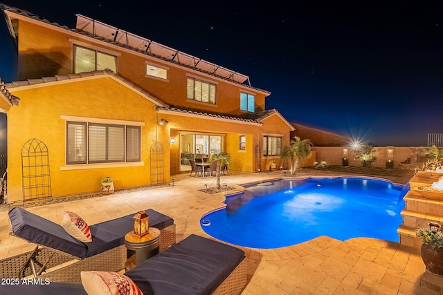 pool at twilight featuring a patio, pool water feature, and a fire pit