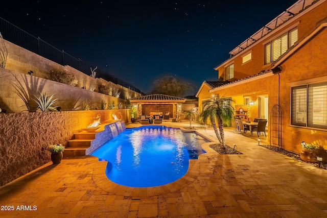 pool at twilight featuring a gazebo, pool water feature, and a patio area