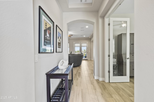 hallway with arched walkways, recessed lighting, visible vents, baseboards, and light wood-type flooring