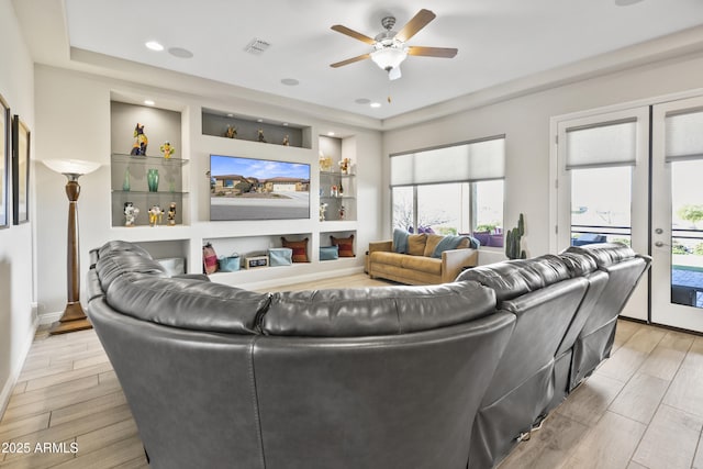 living area with ceiling fan, built in shelves, visible vents, and wood finish floors