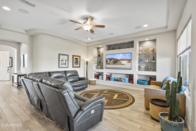 living room featuring arched walkways, built in shelves, visible vents, and wood tiled floor