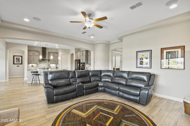 living room with arched walkways, recessed lighting, visible vents, wood tiled floor, and baseboards