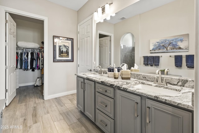 bathroom with double vanity, visible vents, a sink, and wood finished floors