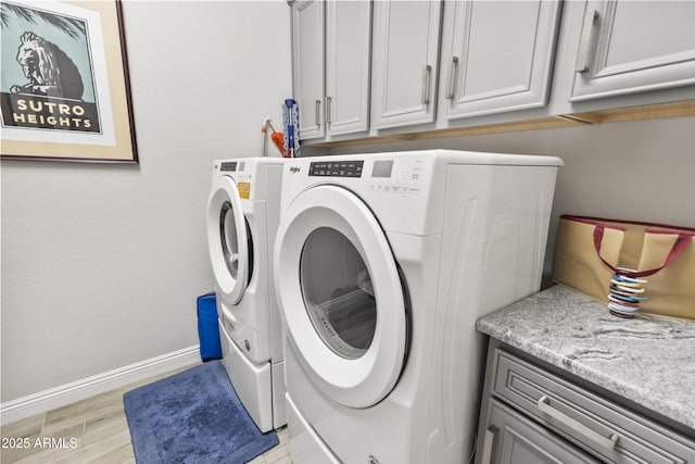 laundry room featuring cabinet space, baseboards, light wood-style floors, and washing machine and clothes dryer