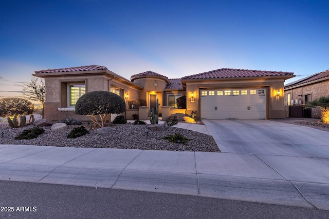 mediterranean / spanish home with driveway, a tiled roof, and stucco siding