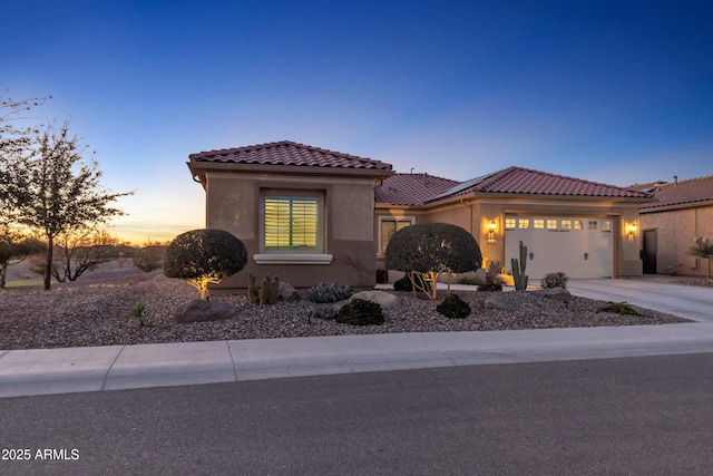 mediterranean / spanish-style home featuring a garage, stucco siding, concrete driveway, and a tiled roof