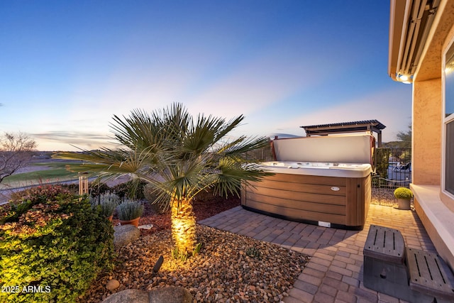 yard at dusk with a patio, fence, and a hot tub