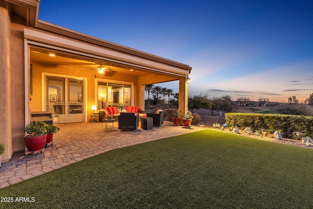 yard at dusk featuring a patio area, ceiling fan, fence, and an outdoor hangout area