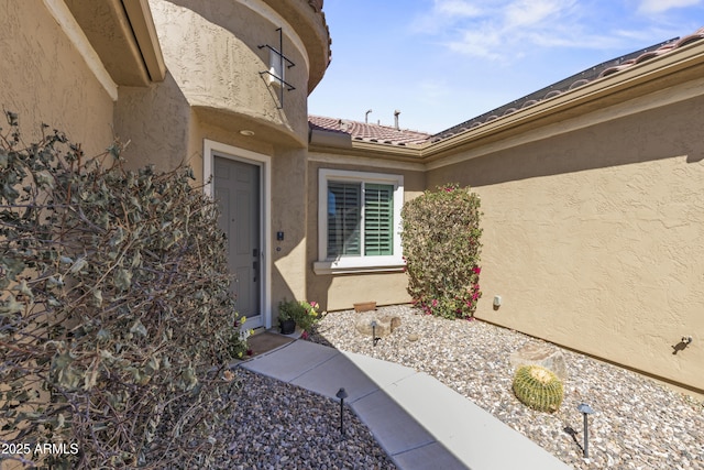 entrance to property with a tile roof and stucco siding