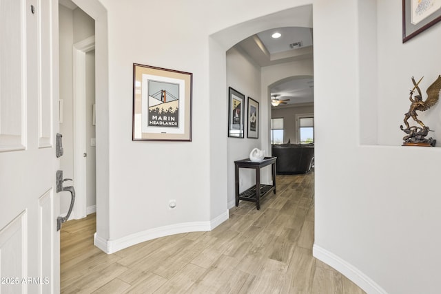 hall with visible vents, arched walkways, baseboards, light wood-style floors, and recessed lighting