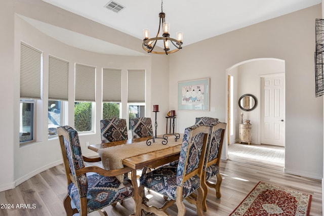 dining space with light hardwood / wood-style floors and an inviting chandelier