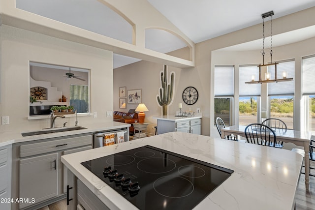 kitchen featuring black electric cooktop, light stone counters, dishwasher, hanging light fixtures, and gray cabinets