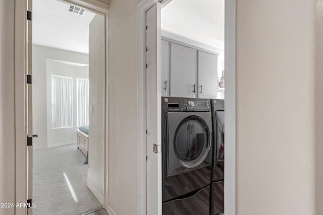 washroom featuring light carpet, cabinets, and washing machine and clothes dryer