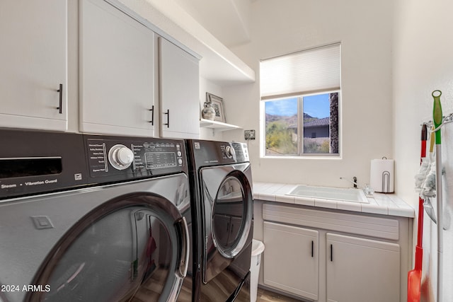 laundry room with cabinets, sink, washer and dryer, and light hardwood / wood-style flooring