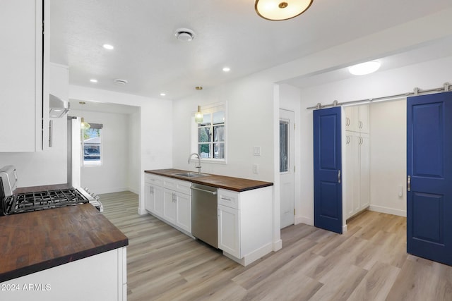 kitchen featuring wood counters, dishwasher, white cabinets, hanging light fixtures, and a barn door