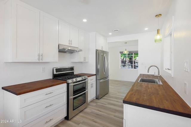 kitchen with wooden counters, sink, appliances with stainless steel finishes, decorative light fixtures, and white cabinetry