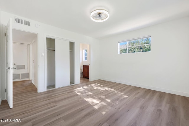 unfurnished bedroom with connected bathroom, light hardwood / wood-style flooring, and a closet