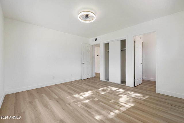 unfurnished bedroom with a closet and light hardwood / wood-style floors