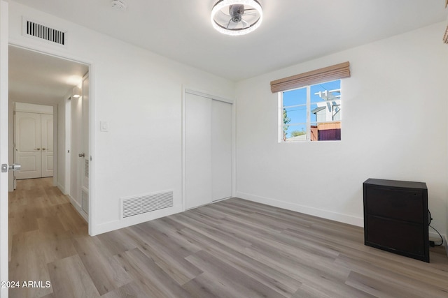 unfurnished bedroom with light wood-type flooring and a closet