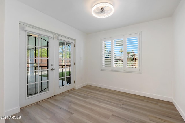 unfurnished room with light wood-type flooring, a wealth of natural light, and french doors