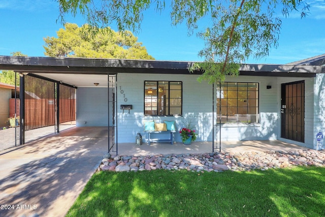 rear view of property with a lawn and a carport