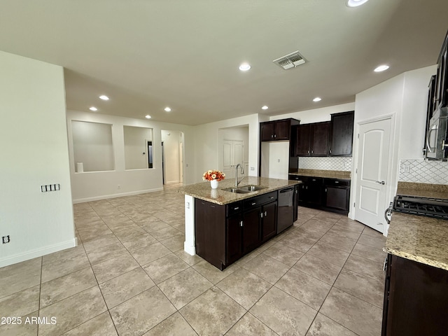 kitchen with light stone counters, dishwasher, decorative backsplash, a kitchen island with sink, and sink