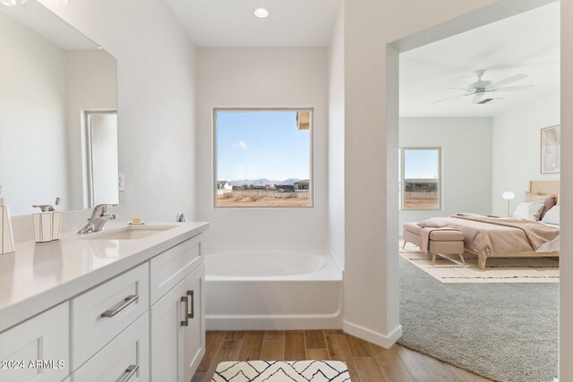 full bathroom featuring vanity, wood finished floors, a ceiling fan, ensuite bath, and a garden tub