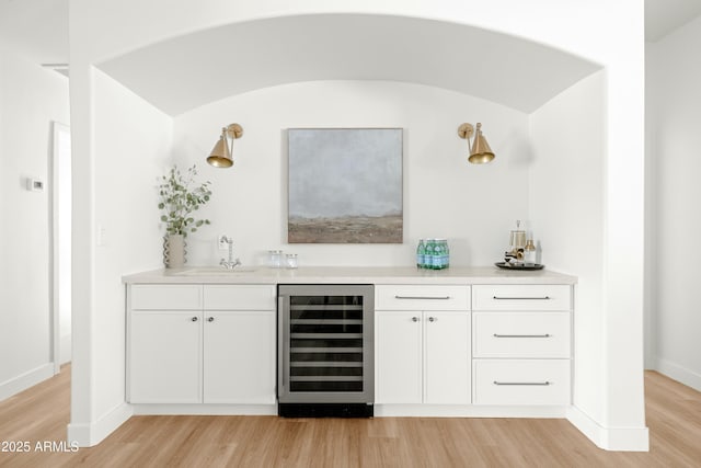 bar with white cabinetry, sink, wine cooler, light hardwood / wood-style floors, and vaulted ceiling