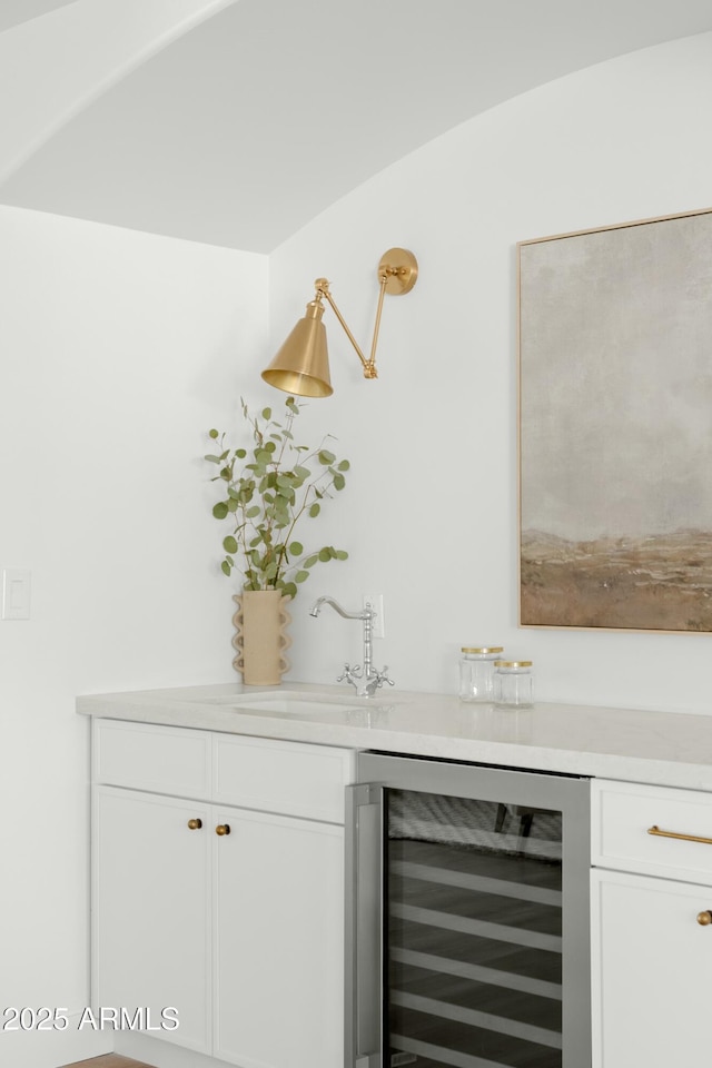 bar featuring white cabinets, beverage cooler, and sink