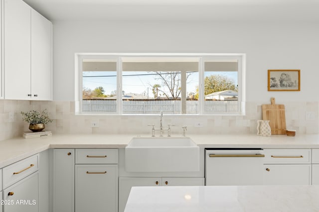 kitchen featuring tasteful backsplash, white cabinetry, white dishwasher, and sink