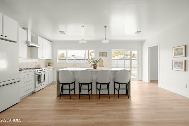 kitchen with white cabinets, white appliances, and hanging light fixtures