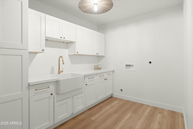 clothes washing area featuring cabinets, washer hookup, electric dryer hookup, sink, and light hardwood / wood-style floors