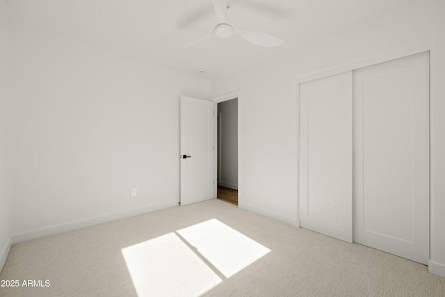 unfurnished bedroom with a closet, light colored carpet, and ceiling fan