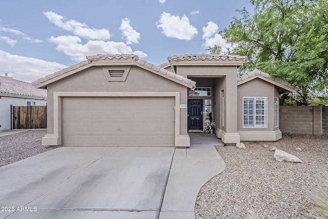 view of front of house with concrete driveway, a tiled roof, an attached garage, and fence