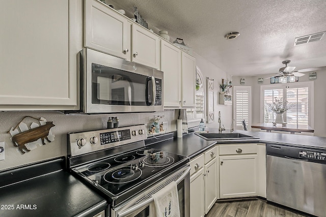 kitchen with a sink, a textured ceiling, visible vents, a ceiling fan, and appliances with stainless steel finishes