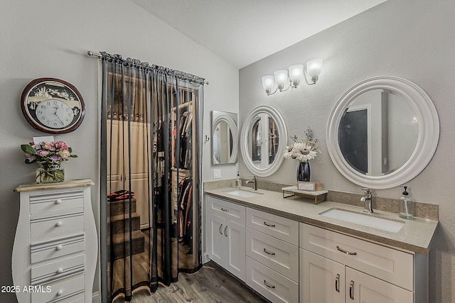 full bathroom featuring a sink, double vanity, lofted ceiling, and wood finished floors