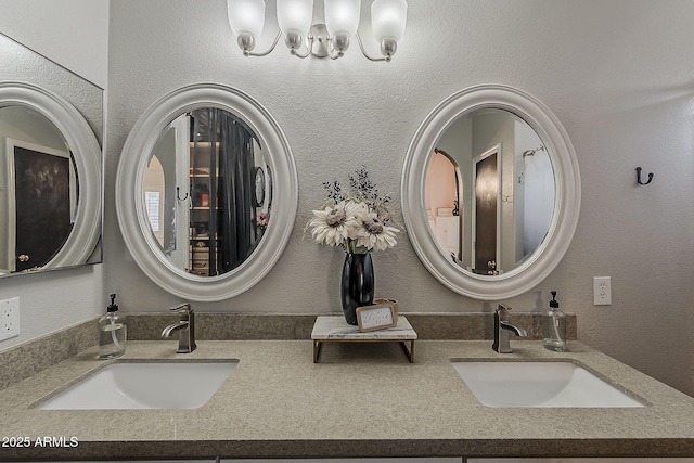 full bath with double vanity, an inviting chandelier, and a sink