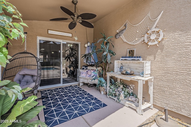 entrance to property with a ceiling fan and stucco siding
