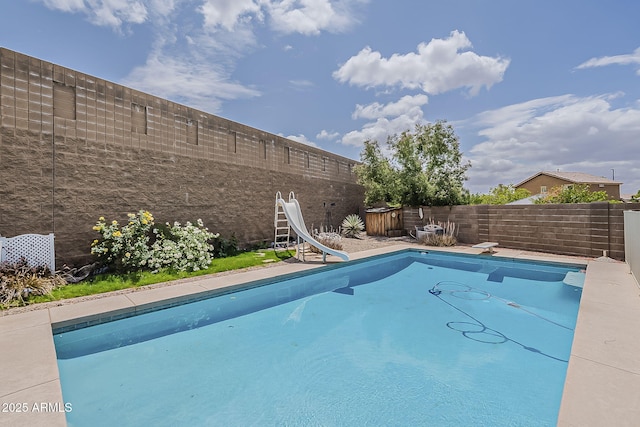 view of swimming pool with a fenced backyard, a fenced in pool, a diving board, and a water slide