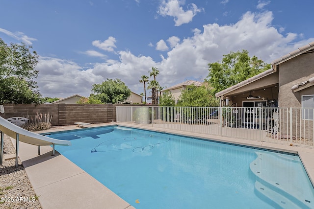 view of swimming pool featuring ceiling fan, fence, a water slide, and a fenced in pool