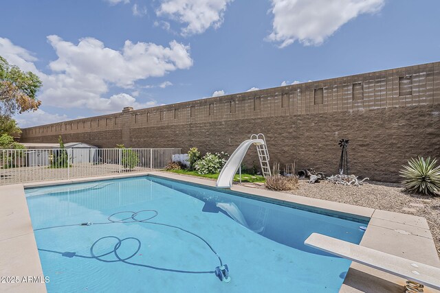 view of pool with a fenced in pool, a diving board, a water slide, and a fenced backyard