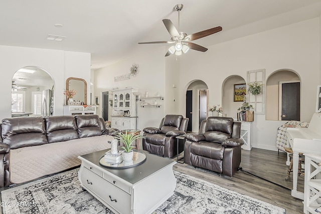 living room featuring arched walkways, visible vents, and a ceiling fan