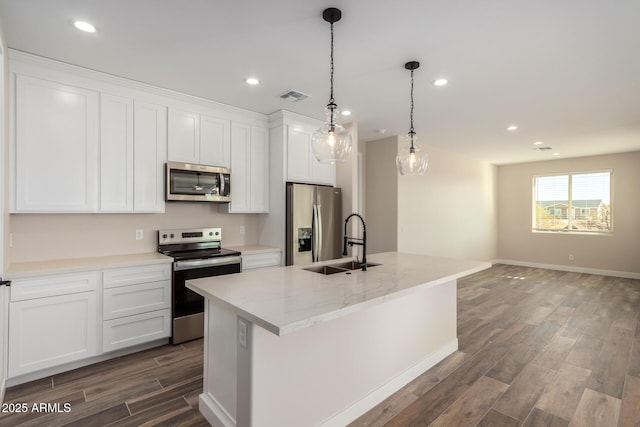 kitchen featuring stainless steel appliances, white cabinets, sink, and an island with sink