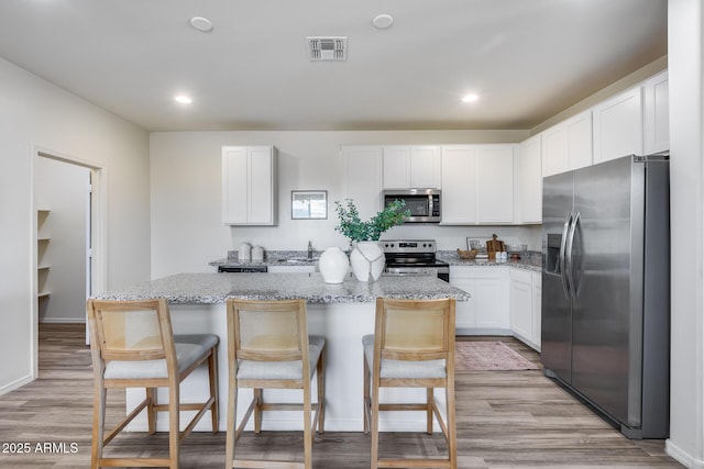 17728 W Paraiso Dr, Surprise, AZ 85387 - kitchen featuring appliances with stainless steel finishes, a sink, a center island, white cabinetry, and light stone countertops