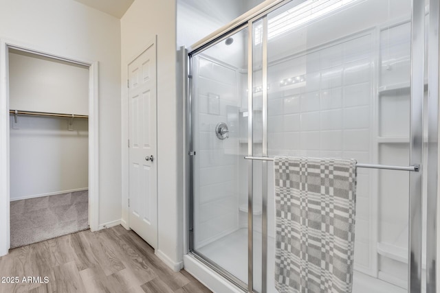 17728 W Paraiso Dr, Surprise, AZ 85387 - bathroom featuring a shower stall, wood finished floors, a walk in closet, and baseboards