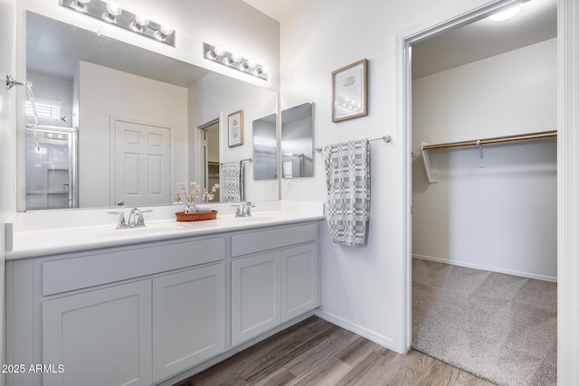 17728 W Paraiso Dr, Surprise, AZ 85387 - full bathroom featuring double vanity, an enclosed shower, a spacious closet, wood finished floors, and baseboards